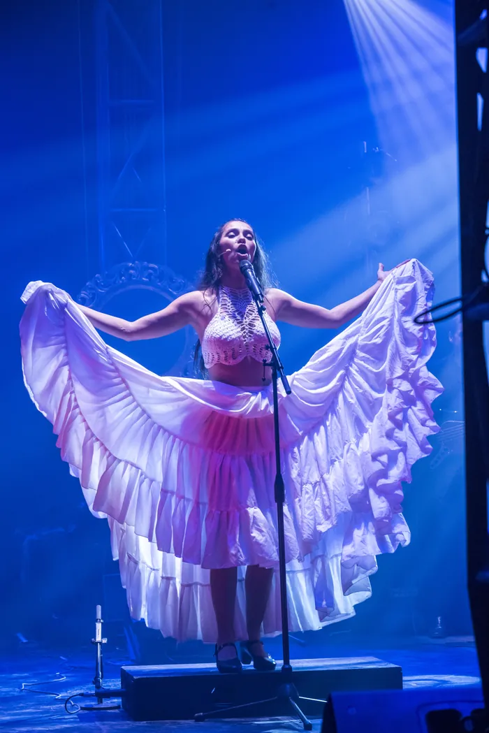 Mamselle Ruiz déploie sa robe blanche comme des ailes sous un faisceau bleu